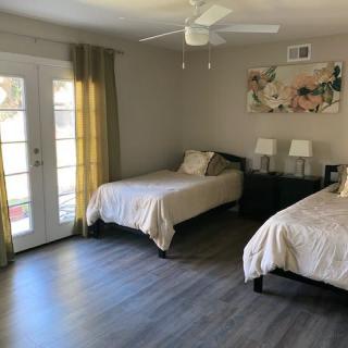 A modern bedroom with twin beds, featuring laminate flooring and natural light from the French doors.