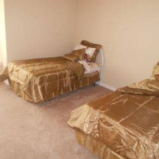 A bedroom with two twin beds dressed in gold-colored bedding.