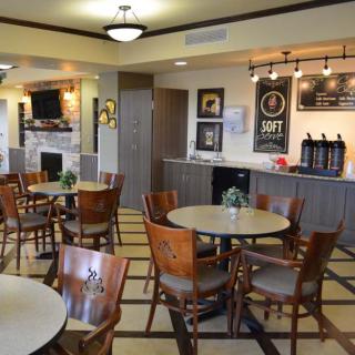 An inviting cafe interior with tables and chairs, featuring a coffee station and warm decor.