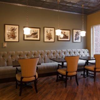 A cozy restaurant interior featuring booth seating, comfortable chairs, and decorated walls with framed art.