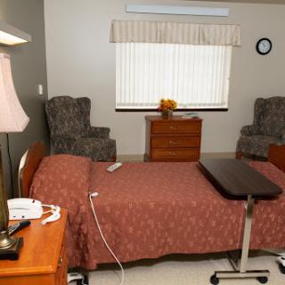 A well-furnished hospital room featuring a bed, seating area, and natural light.