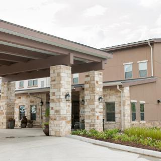 A modern building entrance with stone columns and landscaping.
