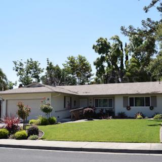 A charming single-family home with well-maintained landscaping and a vibrant front yard.