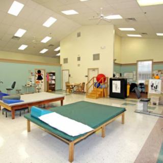 A spacious physical therapy clinic with various equipment and treatment tables.