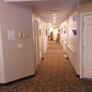 A well-lit hallway with carpet and multiple doors along the sides.