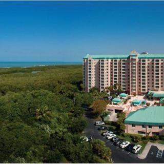 Aerial view of a hotel resort surrounded by lush greenery and overlooking the ocean.