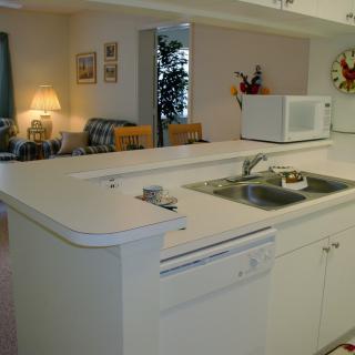 A modern kitchen with white countertops, a sink, and a microwave.