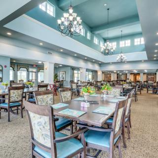 A spacious dining area with elegant chandeliers and neatly arranged tables and chairs.