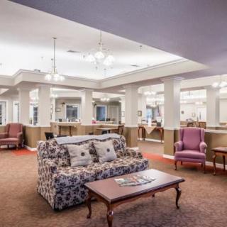 A spacious and elegantly designed lobby with comfortable seating, including a sofa and upholstered chairs, under stylish lighting.