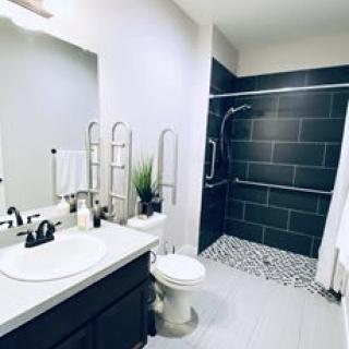 A modern bathroom featuring a sleek sink area, toilet, and spacious shower.