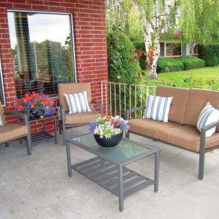 A cozy patio with outdoor furniture including chairs, a sofa, and a table adorned with potted plants.