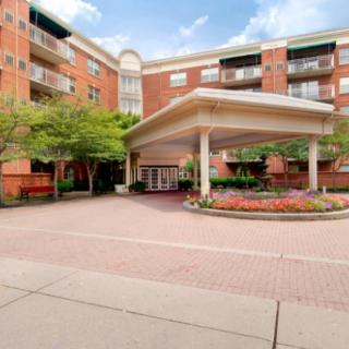 The entrance of a brick hotel with landscaped surroundings and a covered driveway.