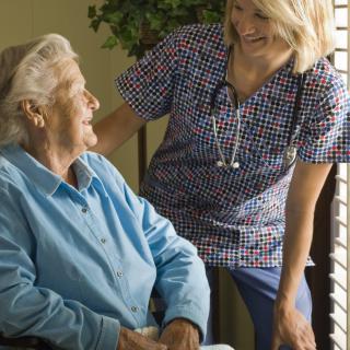 A nurse interacts with an elderly patient in a caring environment.