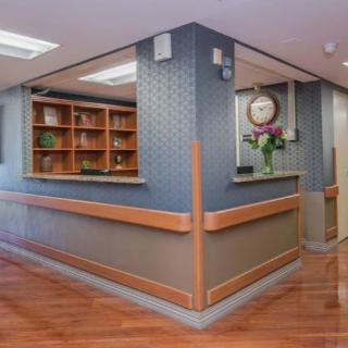 A modern reception area with a wooden desk and shelves.