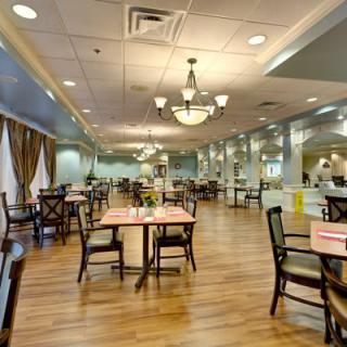 An elegant dining room with neatly arranged tables and chairs, illuminated by chandeliers.