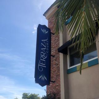 A view of a building with a 'Terraza' restaurant sign and a palm tree in the foreground.