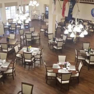A spacious dining area with multiple round tables and elegant lighting fixtures.