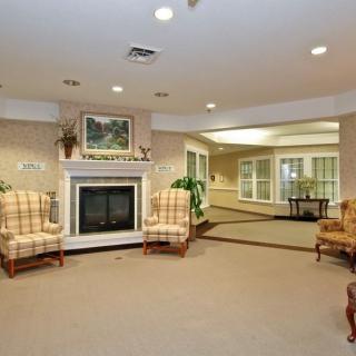 A cozy living room with a fireplace, surrounded by patterned chairs and warm decor.