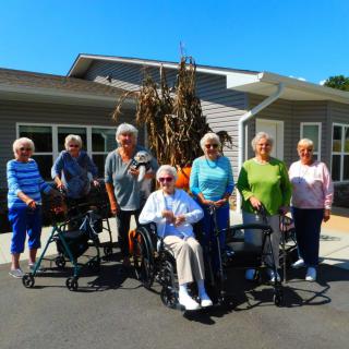 A group of seniors enjoying a sunny day outside a building.