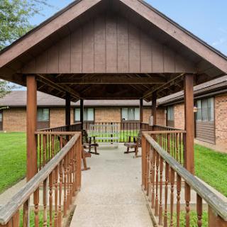 A peaceful walkway leading to a residential building, surrounded by green grass.