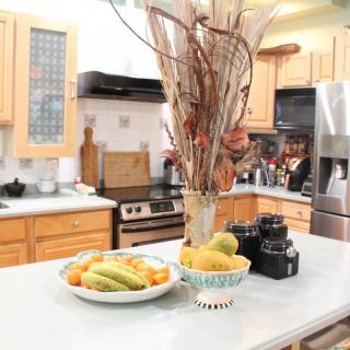 A modern kitchen with fruit and decorative items on the countertop.