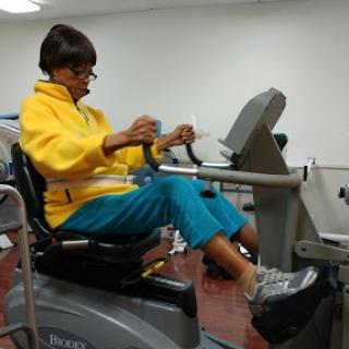 An individual engaging in exercise on a recumbent bike in a rehabilitation setting.