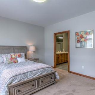 A cozy bedroom with a neatly made bed, bedside lamp, and a painting on the wall.