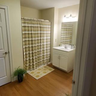 A clean and organized bathroom with a shower, sink, and mirror.