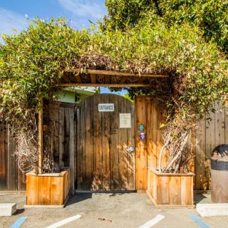 A rustic wooden archway adorned with greenery, marking the entrance to an outdoor area.