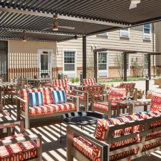 Outdoor patio area with colorful striped cushioned seating and a pergola providing shade.