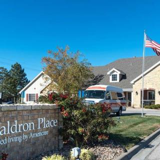A nursing home with an ambulance parked in front, accompanied by a sign and an American flag.