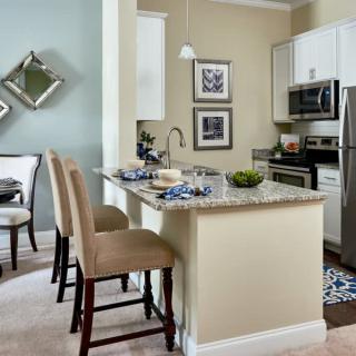 A modern kitchen with bar stools, stainless steel appliances, and stylish decor.