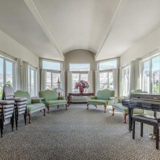 A spacious and bright living room with light green chairs and large windows.