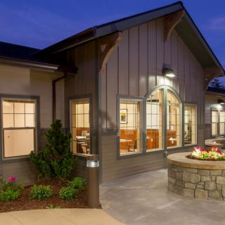 A cozy house exterior illuminated in the evening with a well-maintained patio and landscaping.