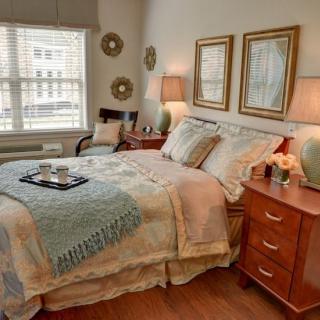 A cozy bedroom with a neatly made bed, wooden nightstands, and warm lighting.