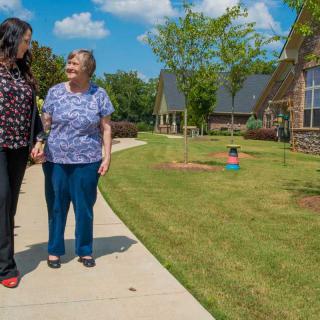 Two people walking together on a sunny day in a community setting.