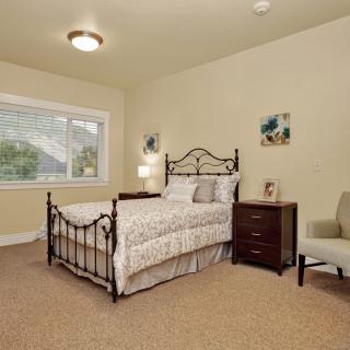 A cozy bedroom with a metal-framed bed, nightstand, and armchair.