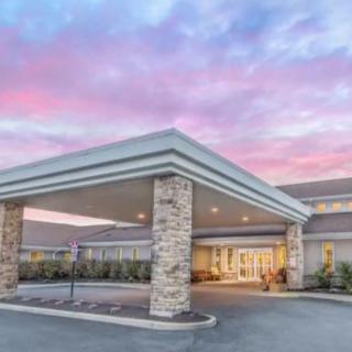 A modern building entrance with a covered driveway, set against a colorful sunset sky.