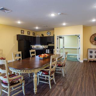 A cozy dining area with a wooden table and chairs, adjacent to a modern kitchen.