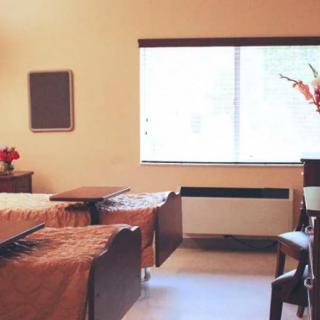 A clean and bright hospital room with two neatly made beds and a window letting in natural light.
