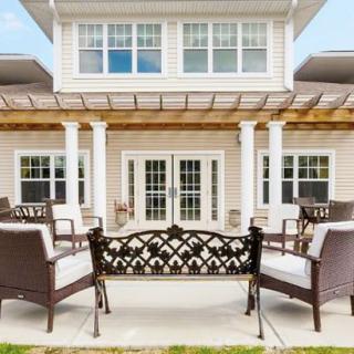 A beautifully designed patio area with outdoor furniture and a pergola, set in front of a stylish house.
