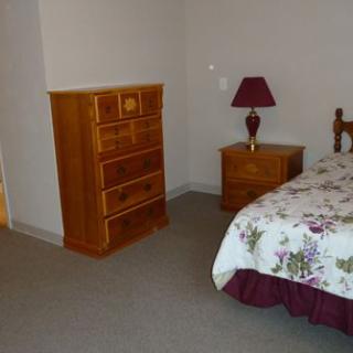 A neatly arranged bedroom with wooden furniture and a floral quilt on the bed.