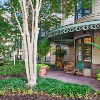 A charming porch surrounded by lush greenery and a garden, featuring outdoor seating.