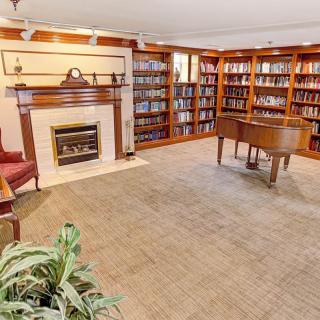 A cozy room with a grand piano, surrounded by bookshelves and a fireplace.