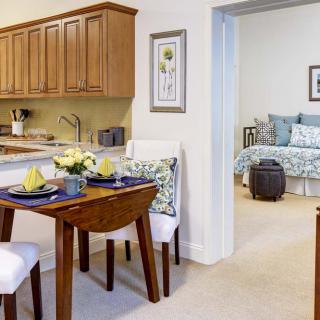 A cozy apartment with an open dining area leading to a bedroom, featuring wood cabinetry and stylish decor.