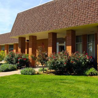 A brick building with a well-maintained garden and lawn.