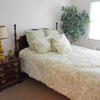 A cozy bedroom featuring a neatly made bed with floral bedding and a stylish nightstand.