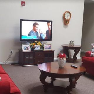 A cozy living room with a television, red sofas, and a wooden coffee table.