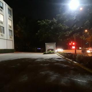 A quiet urban parking lot at night, illuminated by streetlights.