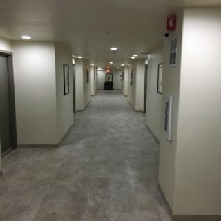 A view of a long, well-lit hallway with multiple doors and elevators.